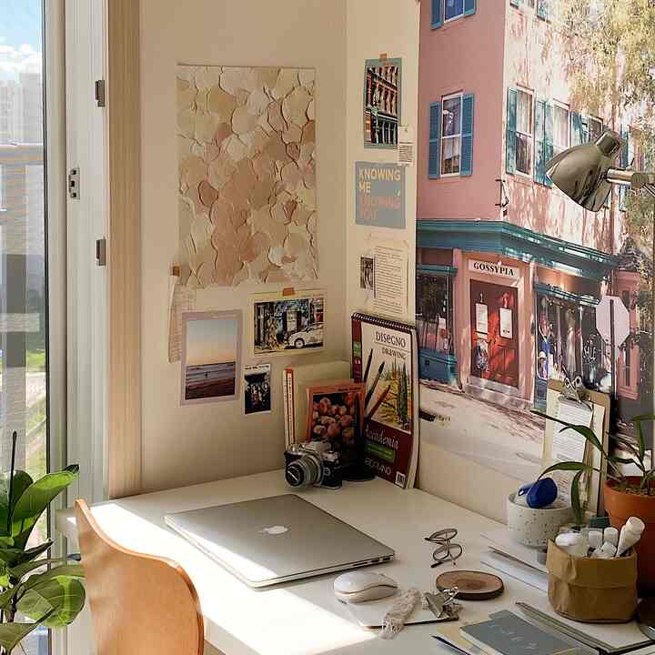 明るいホワイト調のワークスペース、木製の椅子とデスク、壁に掛けられた複数のポスターが配置された雰囲気のあるホームオフィス