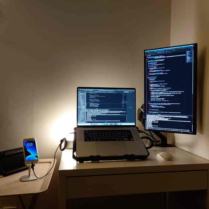 White-toned compact home office featuring a laptop and vertical monitor with a clean workspace setup