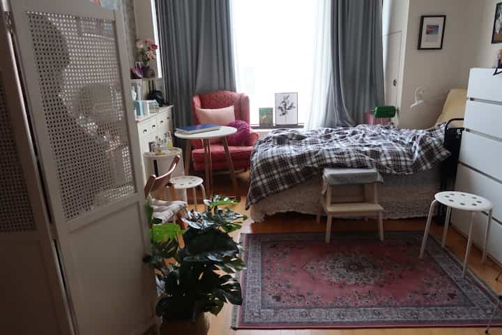 Warm red and white toned bedroom featuring checkered duvet, Persian rug, and cozy armchair creating autumn atmosphere