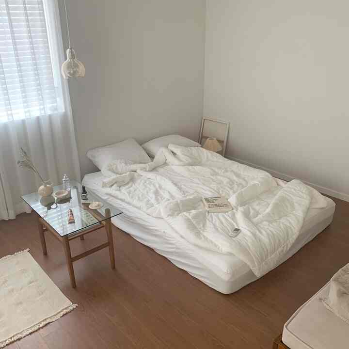 ナチュラルなホワイトトーンの寝室、すっきりとした白いベッドと木目調の床が調和したシンプルな空間