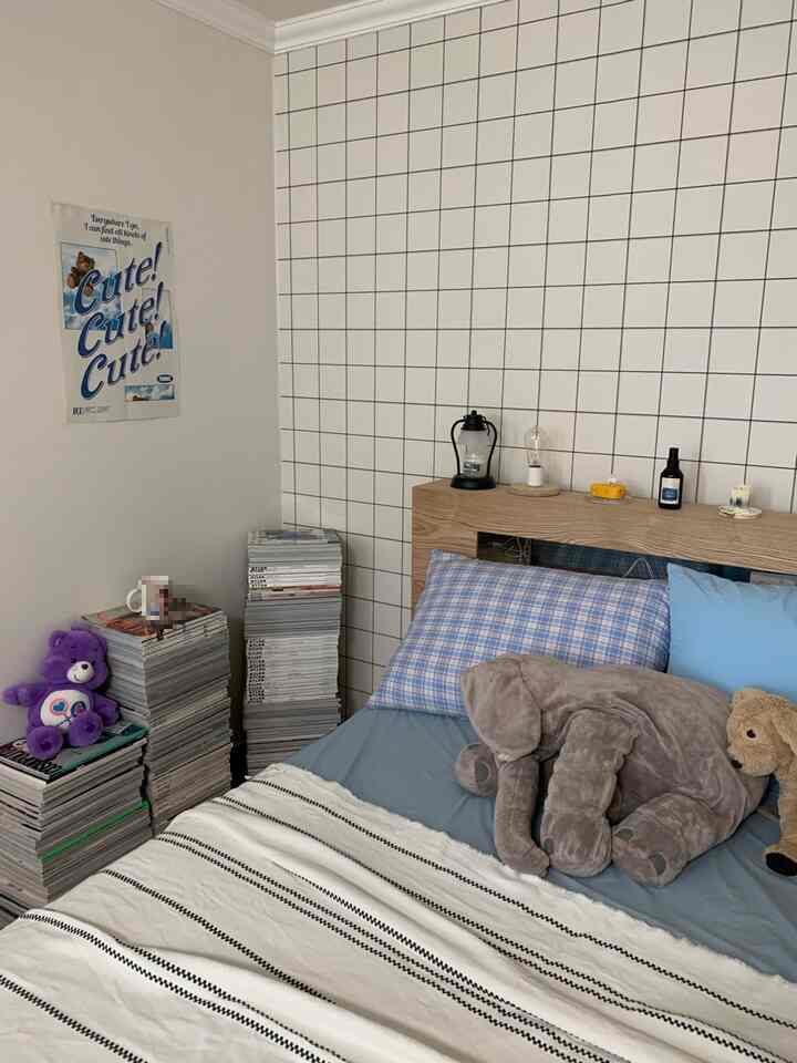White and blue toned bedroom featuring a natural wood bed, plaid pillow, and stuffed toys creating a cozy, simple atmosphere