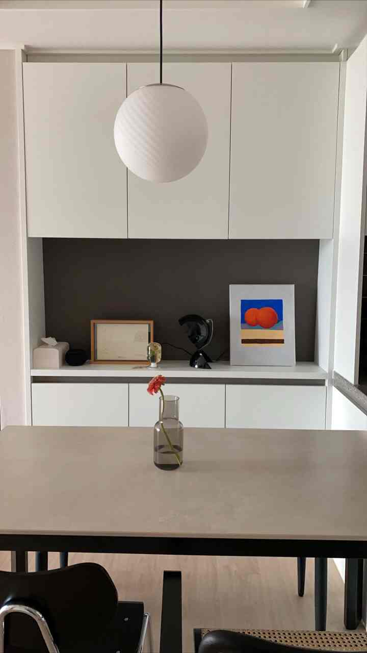 White-toned dining room featuring a simple vase with flower on table, creating a modern and minimalist atmosphere