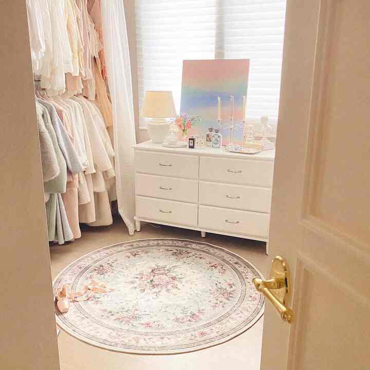 ホワイトとベージュのトーンのウォークインクローゼット、フローラルパターンのラグと6段のドレッサーが配されたエレガントな雰囲気のインテリア