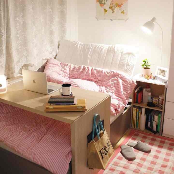 Compact bedroom in pink and beige tones featuring a motion bed and sofa bed creating a cozy atmosphere