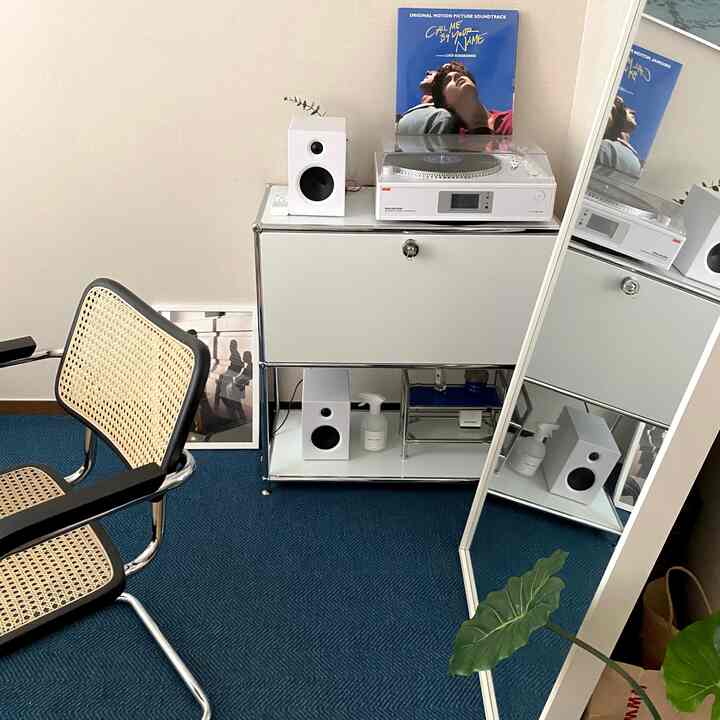 Modern small home office in white and blue tones featuring LP turntable and armchair with a clean layout