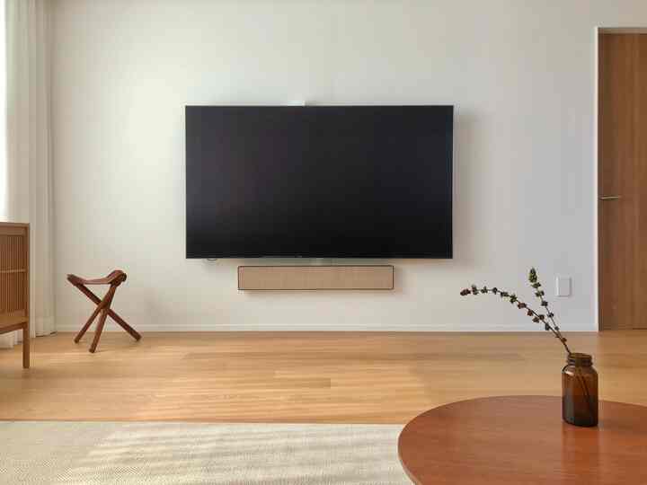 Minimal living room in white and wood tones featuring wall-mounted Samsung TV and Bang & Olufsen soundbar centered on clean wall