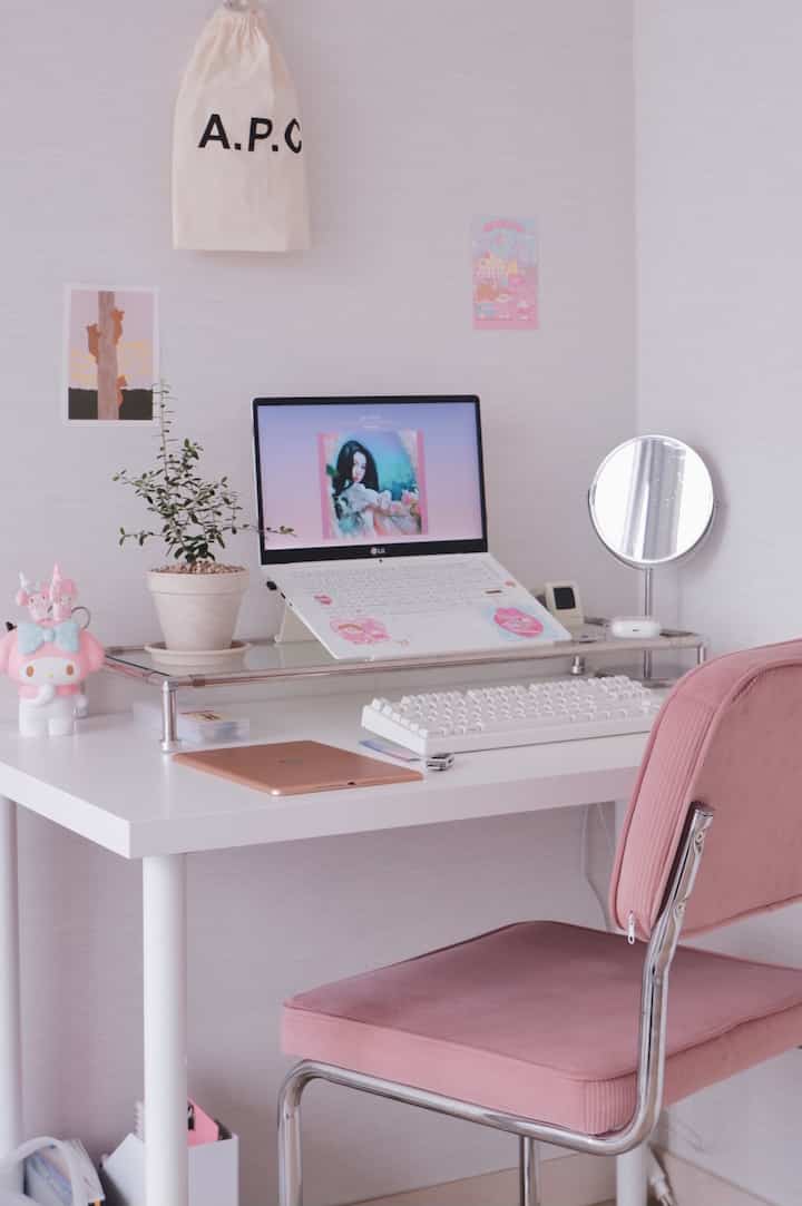 White and pink toned studio apartment home office featuring a pink corduroy chair and white desk creating a cozy atmosphere
