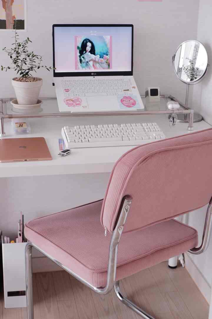 White and pink toned home office space featuring a monitor stand and desk with a cozy and clean work setup