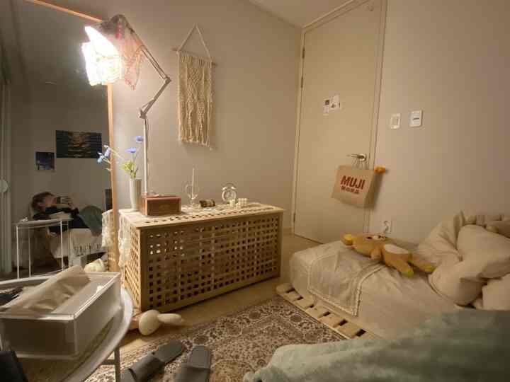 Cozy small bedroom with beige and wood tones, featuring macrame wall hanging and wooden coffee table