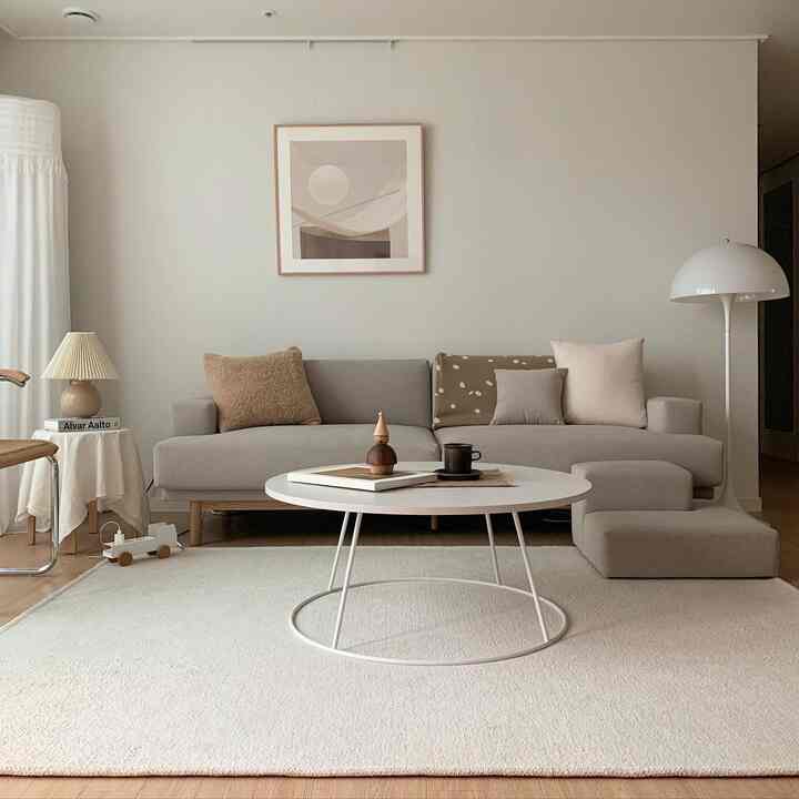 Beige and natural-toned living room featuring an L-shaped sofa, round coffee table, and floor lamp creating a simple modern space
