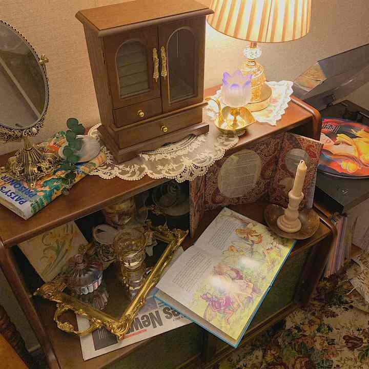 Warm brown-toned vintage style space featuring an elegant mirror and lace-decorated cabinet topped with lighting and trays, creating cozy ambiance