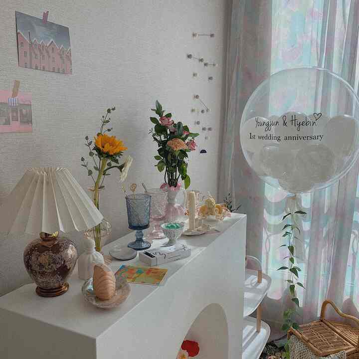 パステル調のリビング、花瓶やヴィンテージ照明、カーテンが配置された温かみのある明るい雰囲気のインテリア