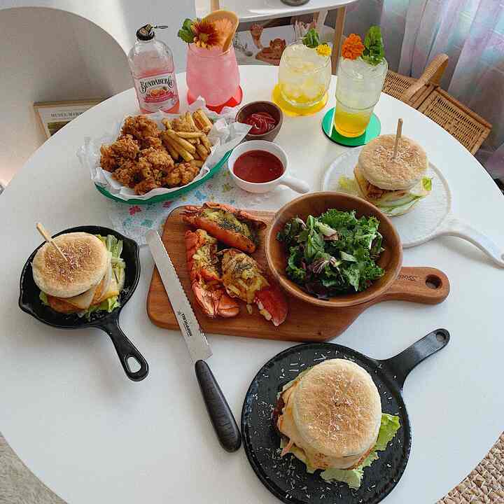 White round table featuring home cafe style fried chicken, fries, burgers, salad and drinks with a natural atmosphere