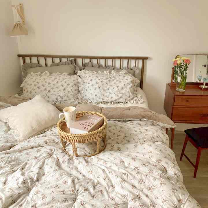 ベージュと木目調の寝室、花柄の寝具とラタンの小物が配置された自然で温かみのあるインテリア