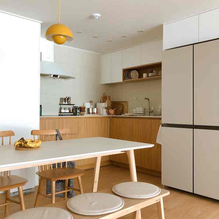 A natural-toned kitchen featuring white and wood elements, with a 6-person dining table and TON chairs arranged neatly