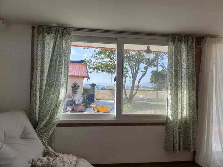 Beige-toned living room with natural sunlight, floral curtains and bean bag sofa creating a cozy space