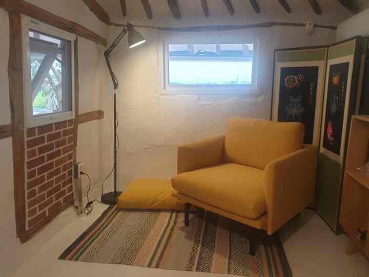 Cozy small study with a yellow sofa and white walls featuring exposed brick accents