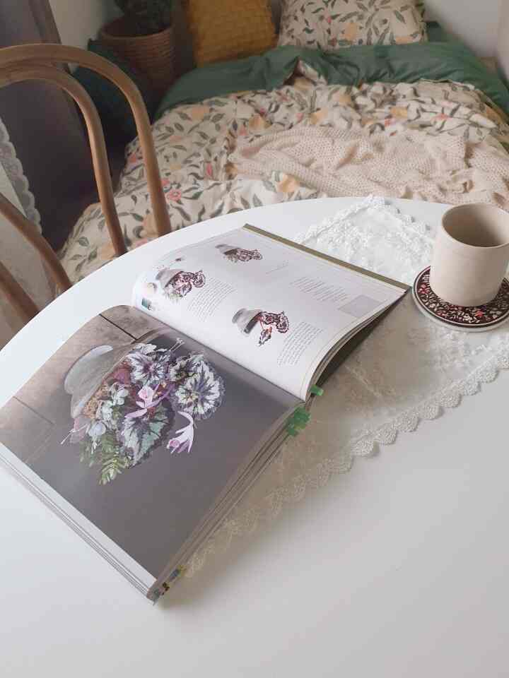 Cozy bedroom space in warm orange and white tones, featuring a round table with book and coffee cup evoking peaceful morning ambiance