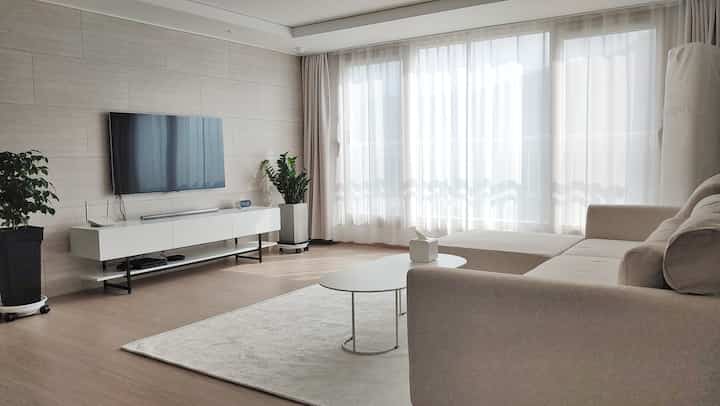 Natural color toned living room with white elements, beige sofa, and sheer curtains creating a cozy atmosphere