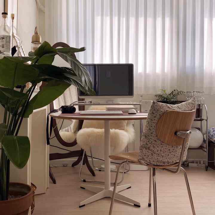 Beige and white toned bedroom with home office setup featuring round desk and mid-century chair in cozy atmosphere