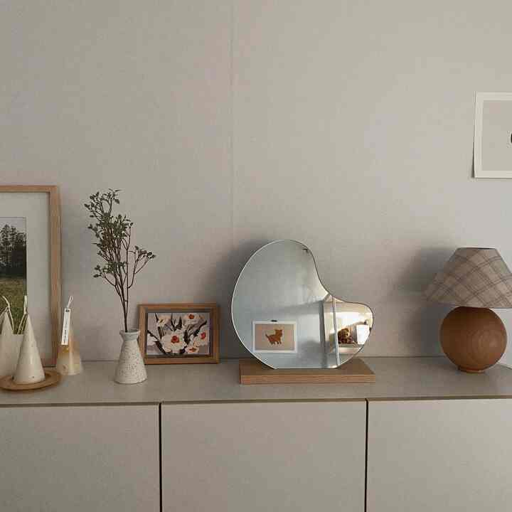 ベージュの壁と木目調の小物が調和したシンプルでナチュラルな印象のリビング収納上部のインテリア