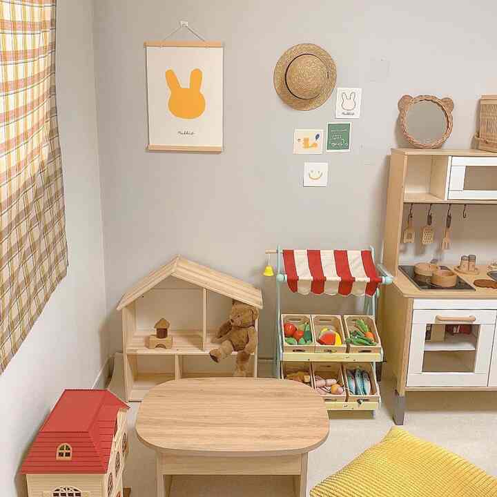 ナチュラルなベージュと黄色のトーンの子供部屋、木製家具とおもちゃ、遊び心のあるポスターが配された雰囲気のあるインテリア