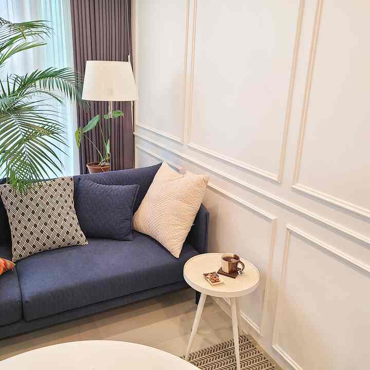 Ivory wainscoting walls with a navy sofa and floor lamp in a simple, modern living room