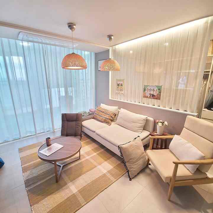 Beige and wood-tone two-person dining room cum home office with subtle rattan pendant lights and sheer curtains creating a cozy atmosphere