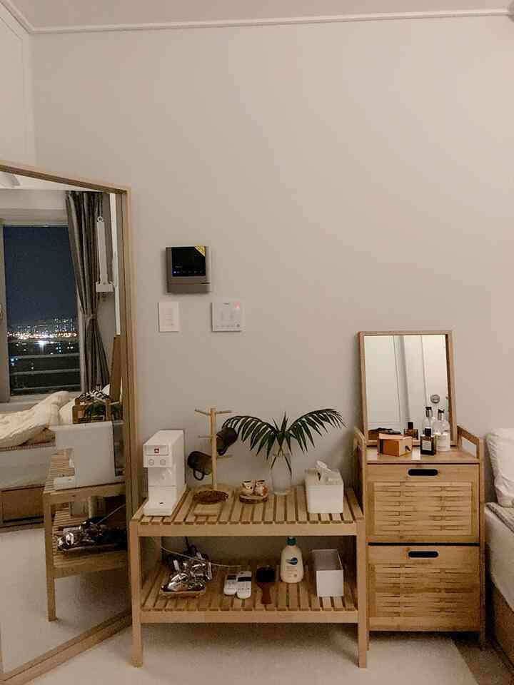 ナチュラルな色調のワンルーム寝室、木製の収納家具と大きな全身鏡が配置された印象的なインテリア