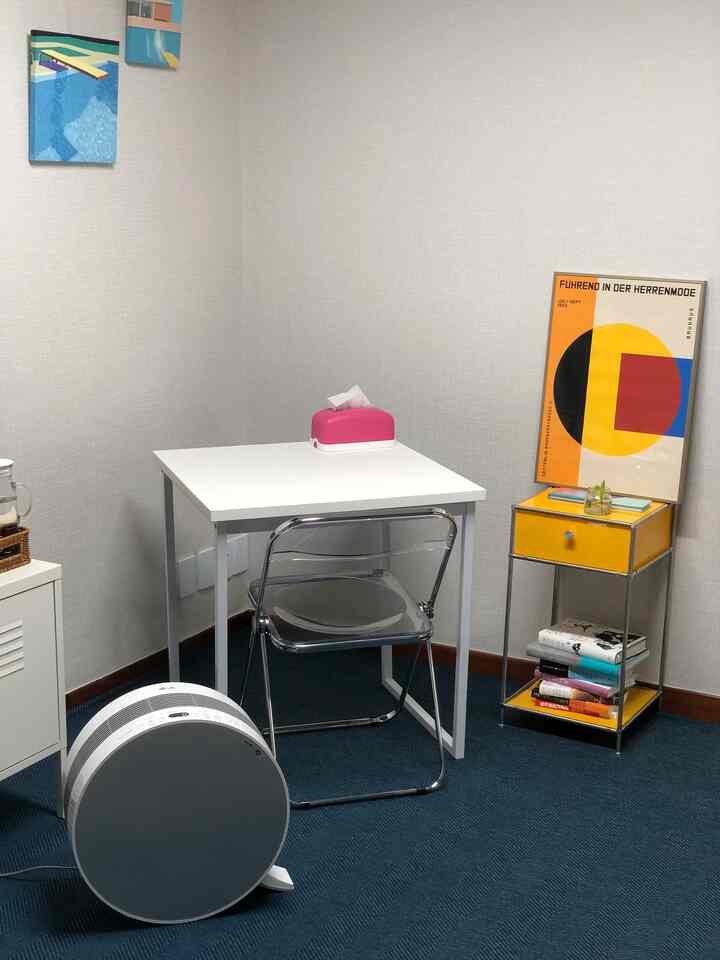 Modern home office space in white and yellow tones featuring a minimal desk, transparent chair, and Bauhaus poster with a clean aesthetic