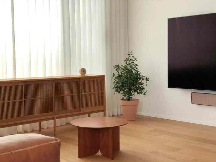 Bright white and wood tone living room featuring a wood living room cabinet and round tea table, with natural and minimal ambiance