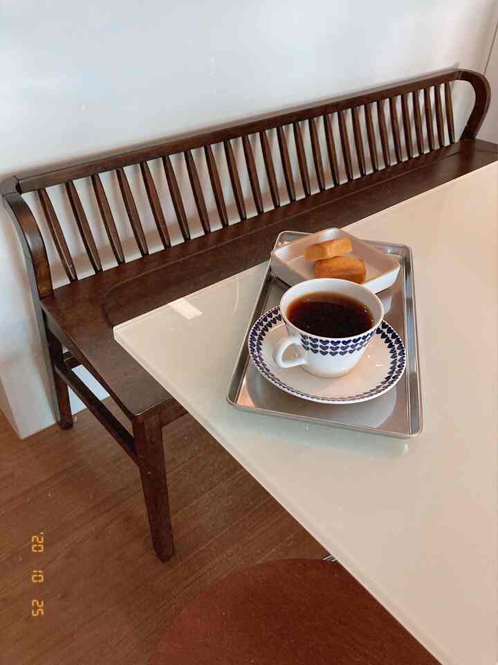 Warm wood-toned dining room featuring a vintage wooden bench and stool, a tray with coffee and snacks on the table, creating a cozy atmosphere