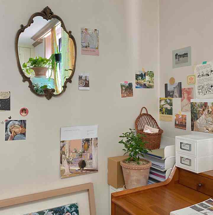 Natural tone living and study space with vintage mirror and postcards, featuring wooden desk and plants creating cozy atmosphere