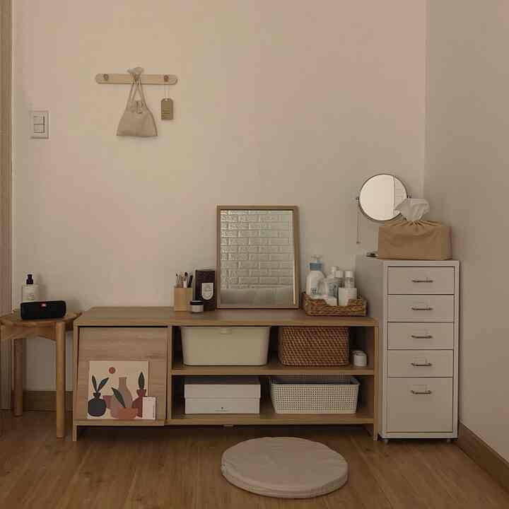 A simple bedroom with a wood-tone floor-style vanity and white storage cabinet, blending natural and white tones.