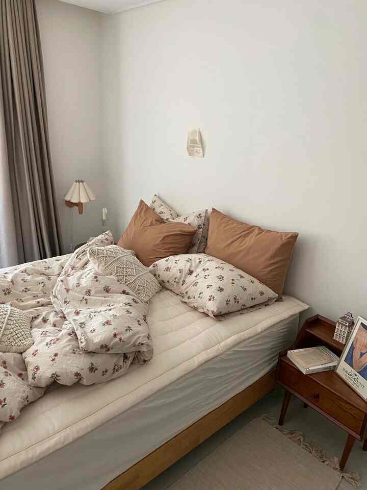 ベージュとホワイトの色調の寝室、木目調のベッドとフローラル柄の寝具が温かみのある秋のインテリアを演出する空間