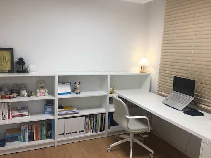 White and wood tone home office with desk and bookshelves arranged in a clean workspace