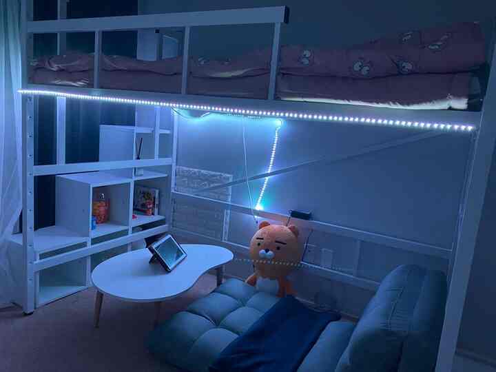 青い照明と白い二段ベッドが配置された子供部屋、ローソファとストリングライトで温かみのあるインテリア