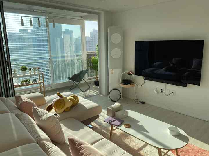 Bright white and beige toned living room featuring a large light beige sofa and simple pendant lights creating a cozy atmosphere