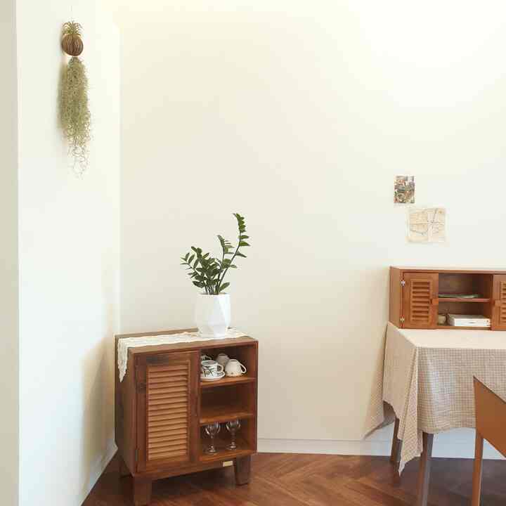 Natural dining room with white walls and wood tone furniture featuring plants and multifunctional storage cabinets