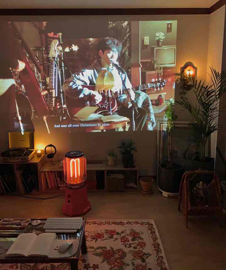 Beige and brown toned living room with a projector displaying video on the wall, featuring plants and vintage decor for a cozy atmosphere