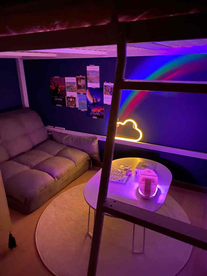 Living room with dark blue walls, gray sofa and round beige rug featuring rainbow mood lighting for cozy atmosphere