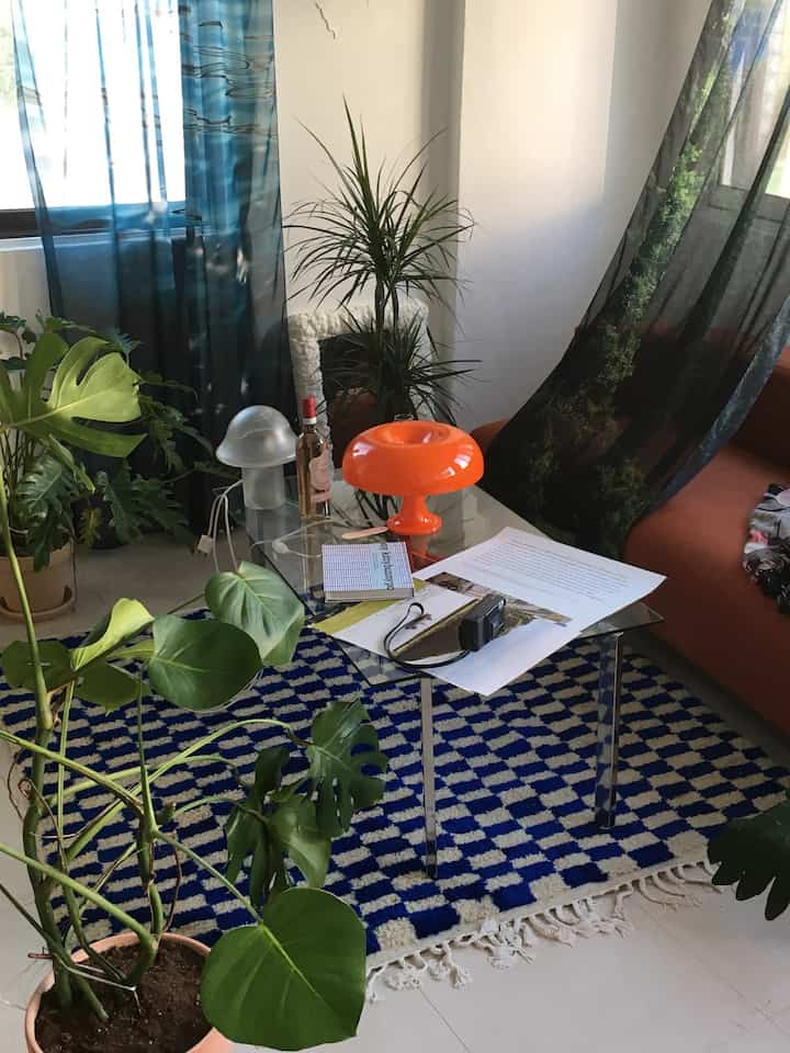 Natural-toned living room featuring orange lighting, sofa, and monstera plants with a cozy atmosphere