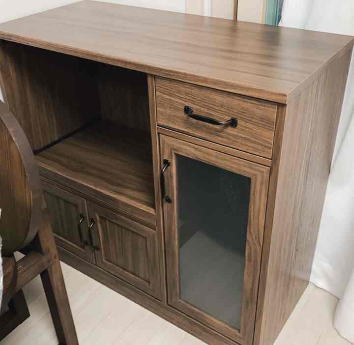 Brown cabinet in a compact kitchen or dining space featuring wood tone with neat and organized interior