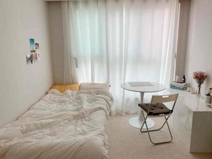 White-toned small bedroom space featuring simple furniture and curtains in a cozy single household room