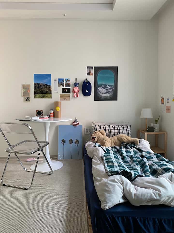 White-walled bedroom space with blue accents, featuring bed, table, and clean natural modern interior
