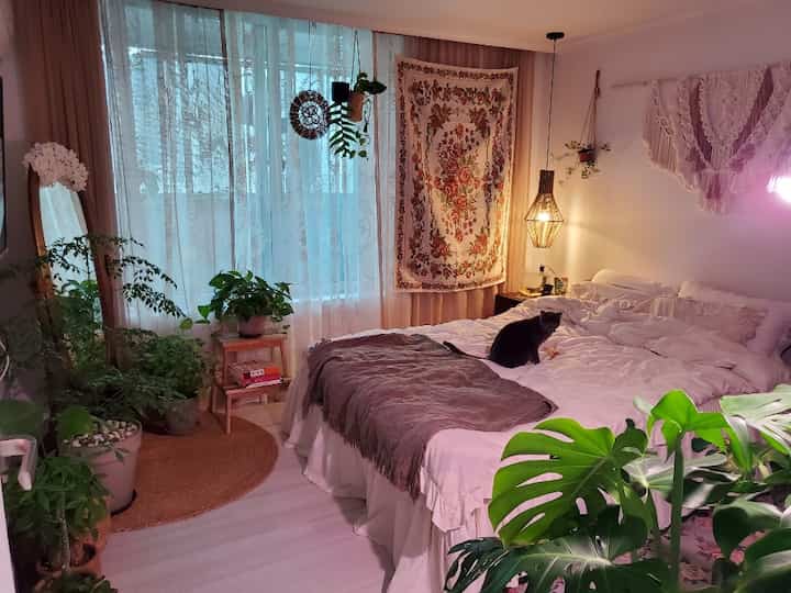 ホワイトとグリーンの色調の寝室、豊富な植物とボヘミアン風の装飾が調和した雰囲気のあるインテリア