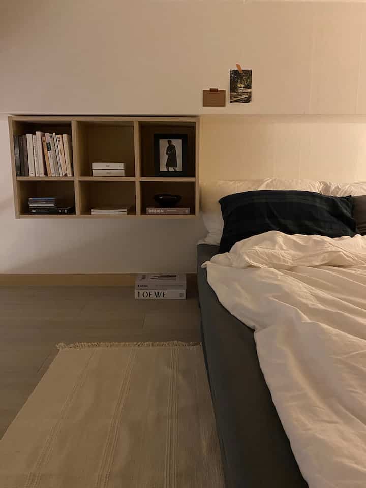 ベージュ系のナチュラルな寝室、壁棚とすっきりとしたベッドが配置された落ち着いた雰囲気のインテリア