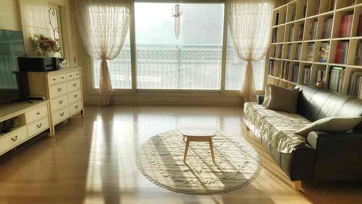 Natural-toned living room with beige and wood tones featuring a sofa and bookshelf with a cozy atmosphere