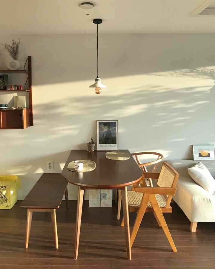 温かみのある木目調と白い壁が調和するダイニング、木製のテーブルとラタンチェアが配置されたナチュラルな空間