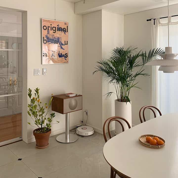 Minimal and natural dining room with white walls, wood tone furniture, and green plants arranged elegantly